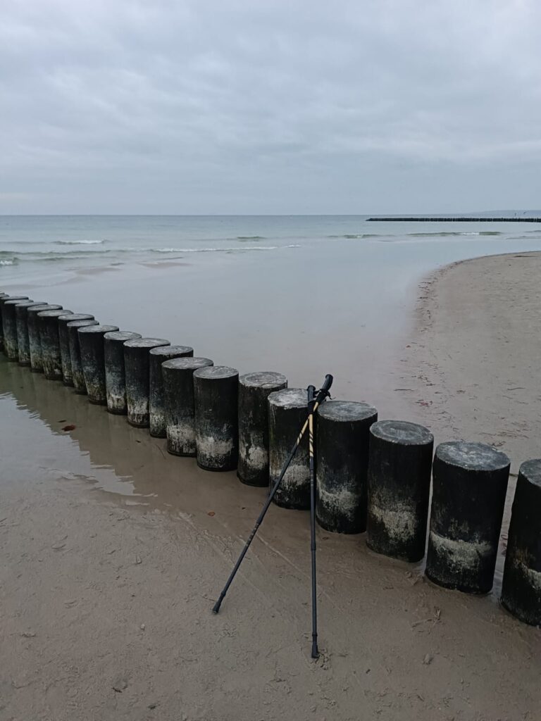 Kije do nordic walking na plaży w Ustce oparte na falochronie. Najlepsza aktywność nad morzem jesienią.